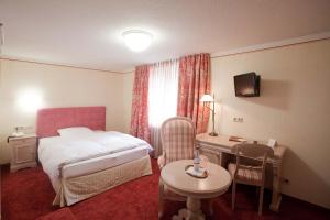 ein Hotelzimmer mit einem Bett, einem Schreibtisch und einem Tisch in der Unterkunft Hotel Karpfen in Eberbach