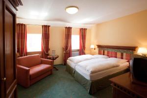 a hotel room with a bed and a chair at Hotel Karpfen in Eberbach