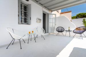 a patio with white chairs and tables on a white wall at Plaka Suites in Plaka Milou