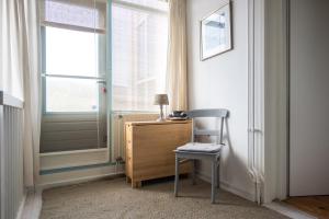 einen Stuhl und einen Schreibtisch in einem Zimmer mit Fenster in der Unterkunft de Vloedlijn in Callantsoog