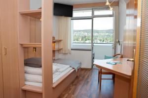 Cette chambre comprend un lit, un bureau et une fenêtre. dans l'établissement Tennis & Yacht Hotel Velden, à Velden am Wörther See