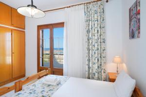 a bedroom with a white bed and a window at Sunset House Skala Maries in Skala Marion