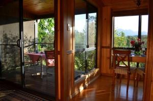 a screened in porch with a table and chairs and windows at Tuckeroo Cottages & Gardens in Rathdowney