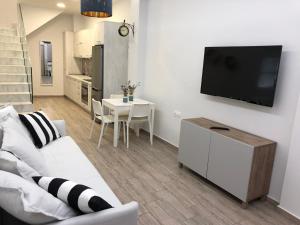 uma sala de estar com um sofá branco e uma televisão na parede em Amari Luxury em Amárion