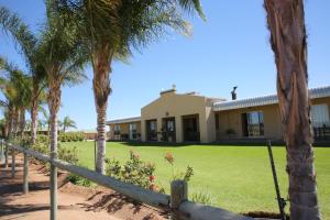 a house with palm trees and a fence at Augrabies De Oude Stoor Guesthouse in Augrabies