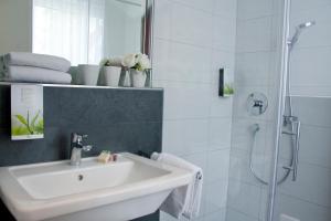 a white bathroom with a sink and a shower at Boardinghouse Landshut in Landshut +12 photos