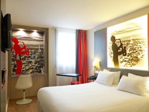 モンティニー・ル・ブルトンヌーにあるベストウェスタン パリ サン カンタンの白い大型ベッドとポスターが備わるホテルルームです。