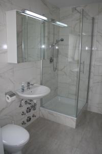 ein Bad mit einer Dusche, einem Waschbecken und einem WC in der Unterkunft Eisberg Gästehaus & De Luxe Appartements in Friesenheim