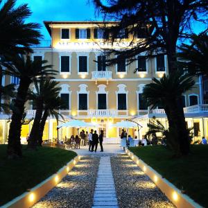 a large white building with palm trees in front of it at Mediterraneo Emotional Hotel & Spa in Santa Margherita Ligure