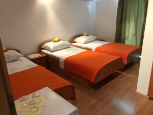 um quarto com duas camas com lençóis laranja e branco em Room Ivana em Neum