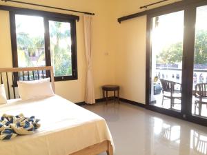 a bedroom with a bed and large windows at Mandhara Chico Bungalow in Lovina
