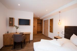 a bedroom with a bed and a desk with a computer at Hotel Schwaiger in Glonn