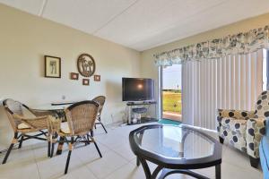 a living room with a table and chairs and a tv at Ocean Watch Oasis in Ormond-by-the-Sea