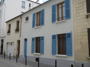 un bâtiment blanc avec volets bleus dans une rue dans l'établissement Chambres d'hôtes Haut de Belleville, à Paris