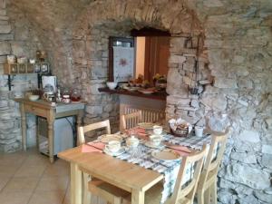 uma mesa numa sala de pedra com uma mesa e cadeiras em B&B Al Ghiro em Villa Lagarina