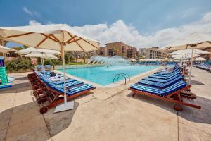 basen z krzesłami, parasolami i fontanną w obiekcie Coral Beach Hotel And Resort Beirut w Bejrucie