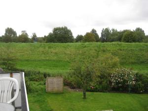 a garden with a hill in the background with a tree at Haus Kuhlmann in Büsum