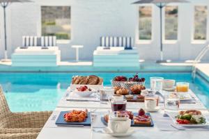 a table with food on it next to a swimming pool at Mrs. Armelina by Mr&Mrs White Hotels in Naousa