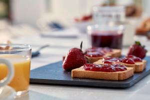 a plate of toast with strawberries and a glass of orange juice at Mrs Armelina by Mr and Mrs White in Naousa +24 photos