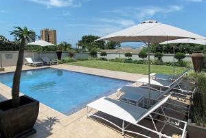 a swimming pool with two chairs and an umbrella at uShaka Manor Guest House in Durban