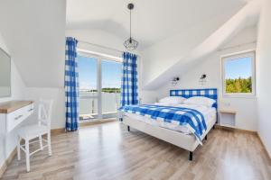 a bedroom with a blue and white bed and windows at Apartamenty Sun & Snow Seaside Grzybowo in Grzybowo