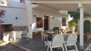 een patio met witte stoelen, een tafel en een open haard bij Mediterranean in Terrasini