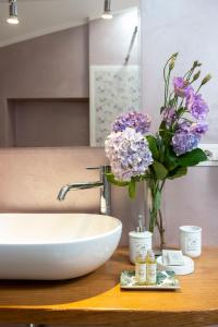La salle de bains est pourvue d'un lavabo avec un vase de fleurs sur un comptoir. dans l'établissement La Casa di Gelda, à Montalcino