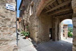um edifício de pedra com uma placa de rua ao lado em La Casa di Gelda em Montalcino