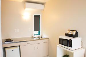 a kitchen with a microwave and a sink at Rayland Motel in Auckland