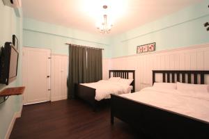 a bedroom with two beds and a tv in it at Antique B&B in Hengchun South Gate