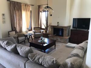 a living room with a couch and a tv at M Varkes Villa in Nea Moudania