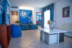 Assinos Palace Hotel في جيارديني ناكسوس: غرفة معيشة مع جدران زرقاء وطاولة مع الزهور