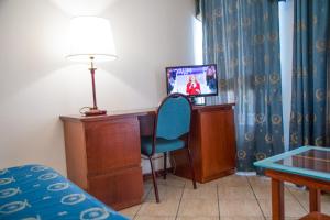 a room with a desk and a bed and a television at Assinos Palace Hotel in Giardini Naxos