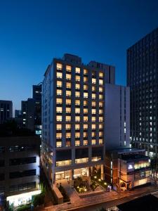 un bâtiment éclairé dans une ville la nuit dans l'établissement Hotel NewV, à Séoul