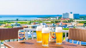 een tafel met drie glazen bier op een balkon bij Hotel Sunset ZANPA in Yomitan