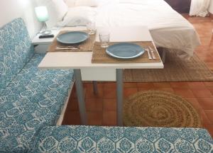 a table with two blue plates on it next to a bed at Apartamentos Albertos in Santa Eularia des Riu