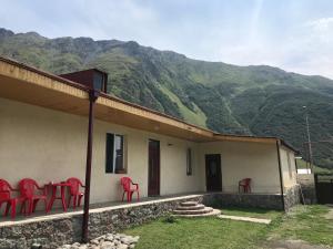 a house with red chairs and a table with mountains at Kazbegian Host in Kazbegi
