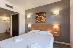 um quarto com uma grande cama branca e 2 almofadas em Residhotel Le Grand Prado em Marselha