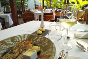 a plate of food on a table with a glass of wine at Ocean Villas Hotel in Grand-Baie