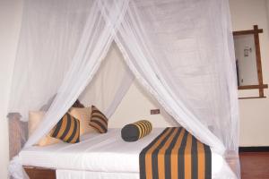 a white canopy bed with pillows and curtains at Ella River Face Inn in Ella