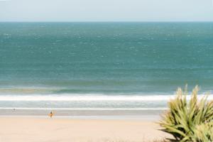 a person walking on the beach with a surfboard at The Penellen guest accommodation room only in Hayle