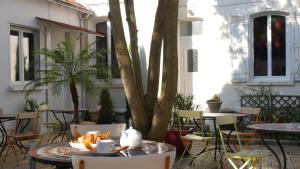 a patio with tables and chairs and a tree at Hôtel Savary in La Rochelle