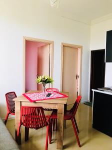 a dining room table with red chairs and a vase with flowers at BSG Rustaveli 184 in K'obulet'i