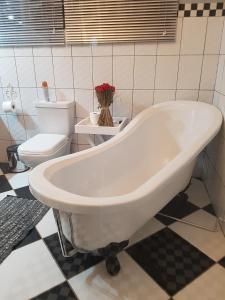 een badkamer met een wit bad en een toilet bij Graceland Guesthouse in Potchefstroom