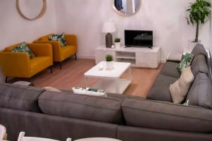 salon z brązową kanapą i żółtymi krzesłami w obiekcie Real Beds Madrid w Madrycie