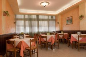 Hotel Centrale di Paolo e Cinzia في لوريتو: مطعم فيه طاولات وكراسي في الغرفة