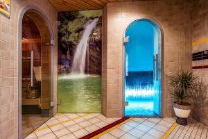 La salle de bains est pourvue d'une fresque murale représentant une cascade située derrière une porte bleue. dans l'établissement Hotel Astoria, à Arosa