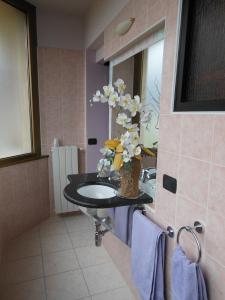 ein Badezimmer mit einem Waschbecken und einer Vase aus Blumen in der Unterkunft Motel Monterosa in Vogogna