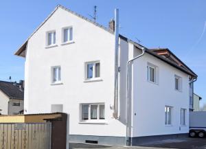 une maison blanche avec une clôture devant elle dans l'établissement Exclusiv Apartment Rödermark 3 Schlafzimmer, à Rödermark