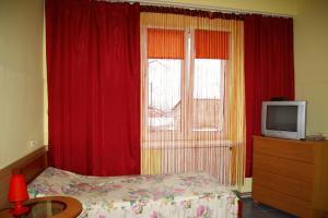 a bedroom with a bed and a window with red curtains at Pokoje Goscinne Koral in Radomsko